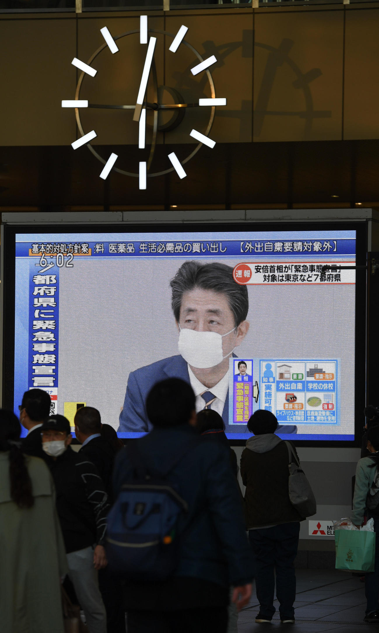 安倍首相の緊急事態宣言発令を伝えるニュースを足を止めてみる人々（2020年4月7日撮影）