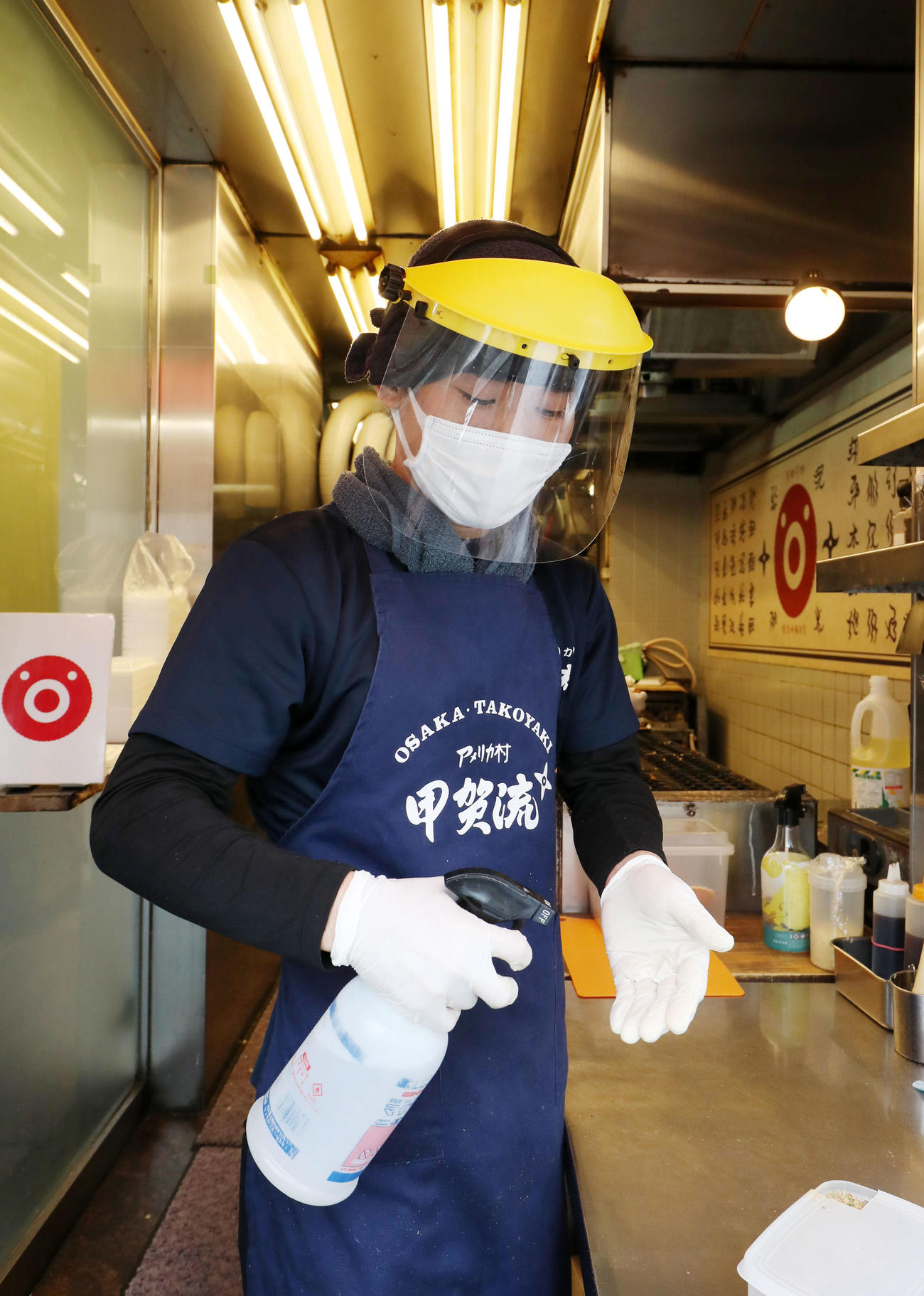 たこ焼きを作る前にはマスクにフェイスガードを装着し、必ずゴム手袋をはめた手をアルコールで消毒する（撮影・加藤哉）