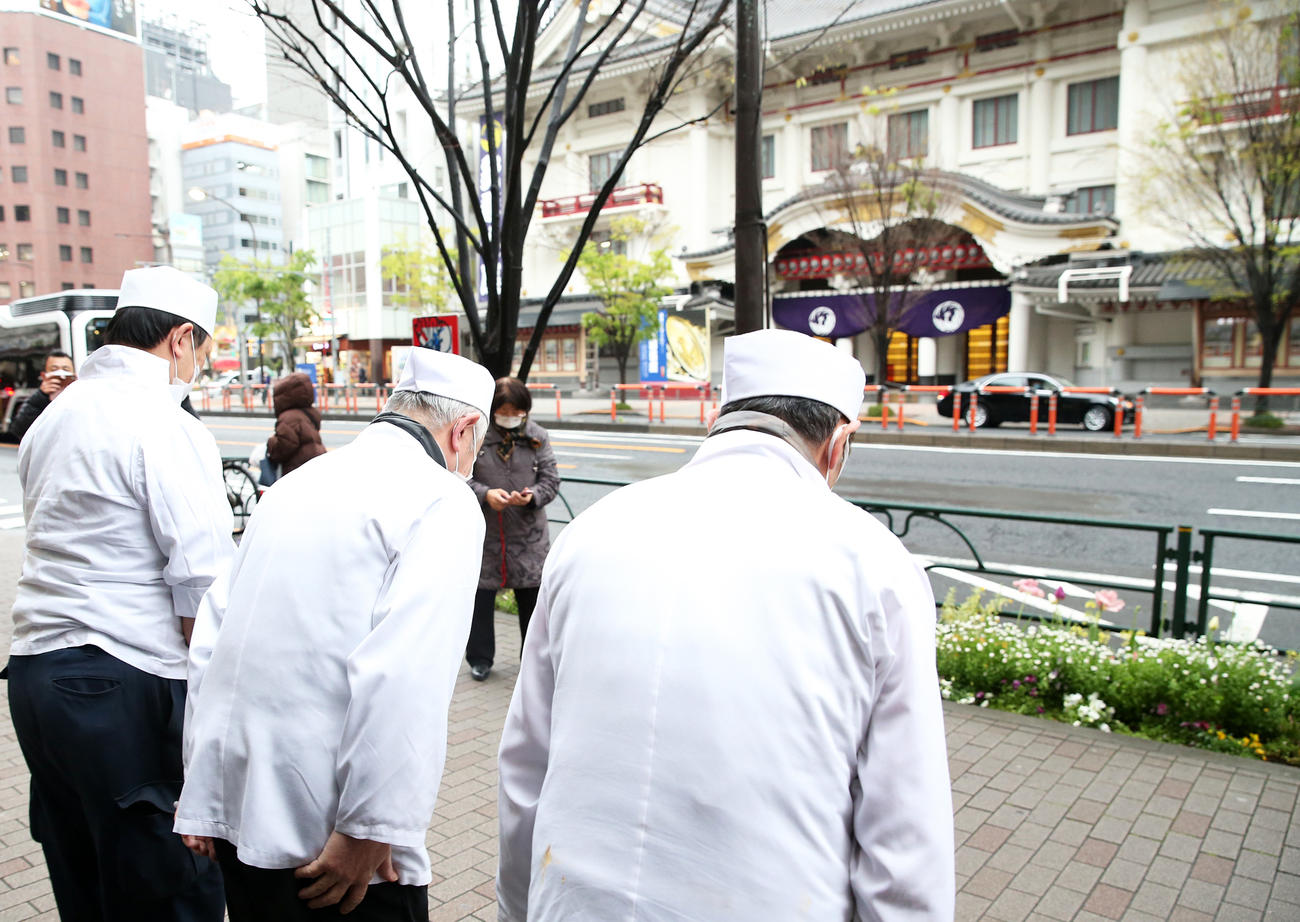 店舗の前で歌舞伎座に向かって一礼する「木挽町辨松（こびきちょうべんまつ）」の猪飼信夫社長（中央）。右は弟の猪飼克二郎さん、左は小島健資専務（撮影・河野匠）