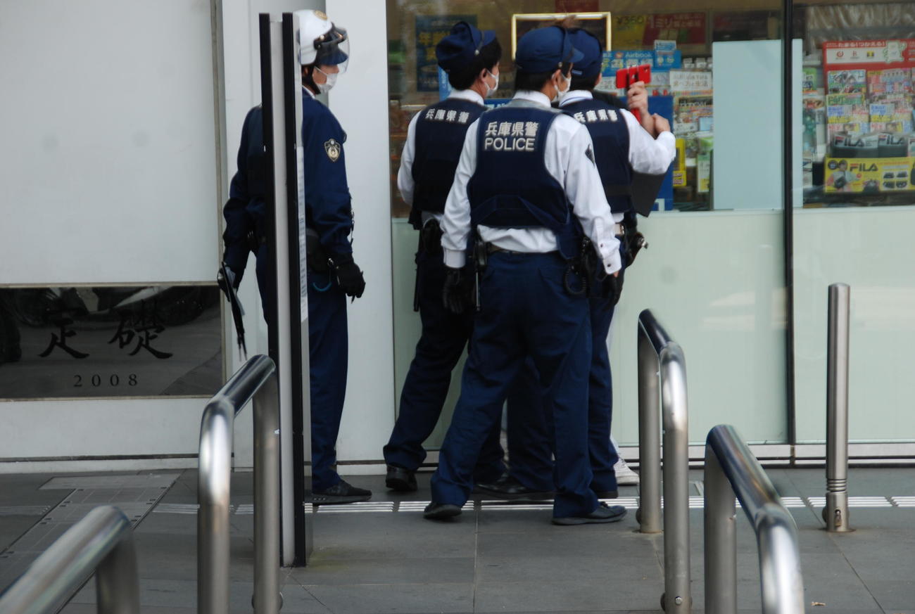 神戸市内の大型パチンコ店の近くでスマホを左手に持つ男が警察官に取り囲まれる（撮影・松浦隆司）