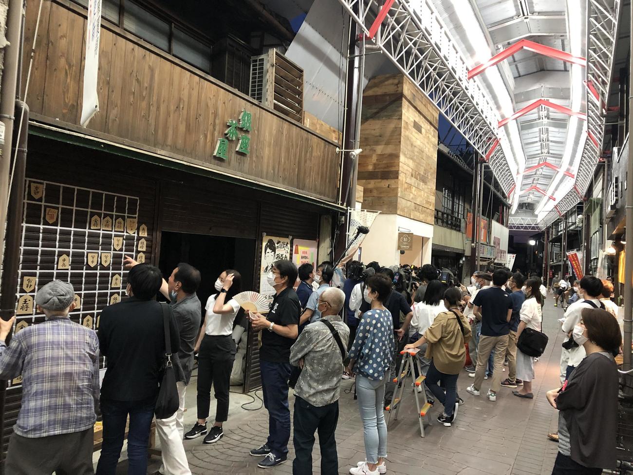 店舗のシャッターにジャンボ将棋盤が張り付けられた「大盤解説」を見ながら応援する地元の人々（せと銀座通り商店街提供）