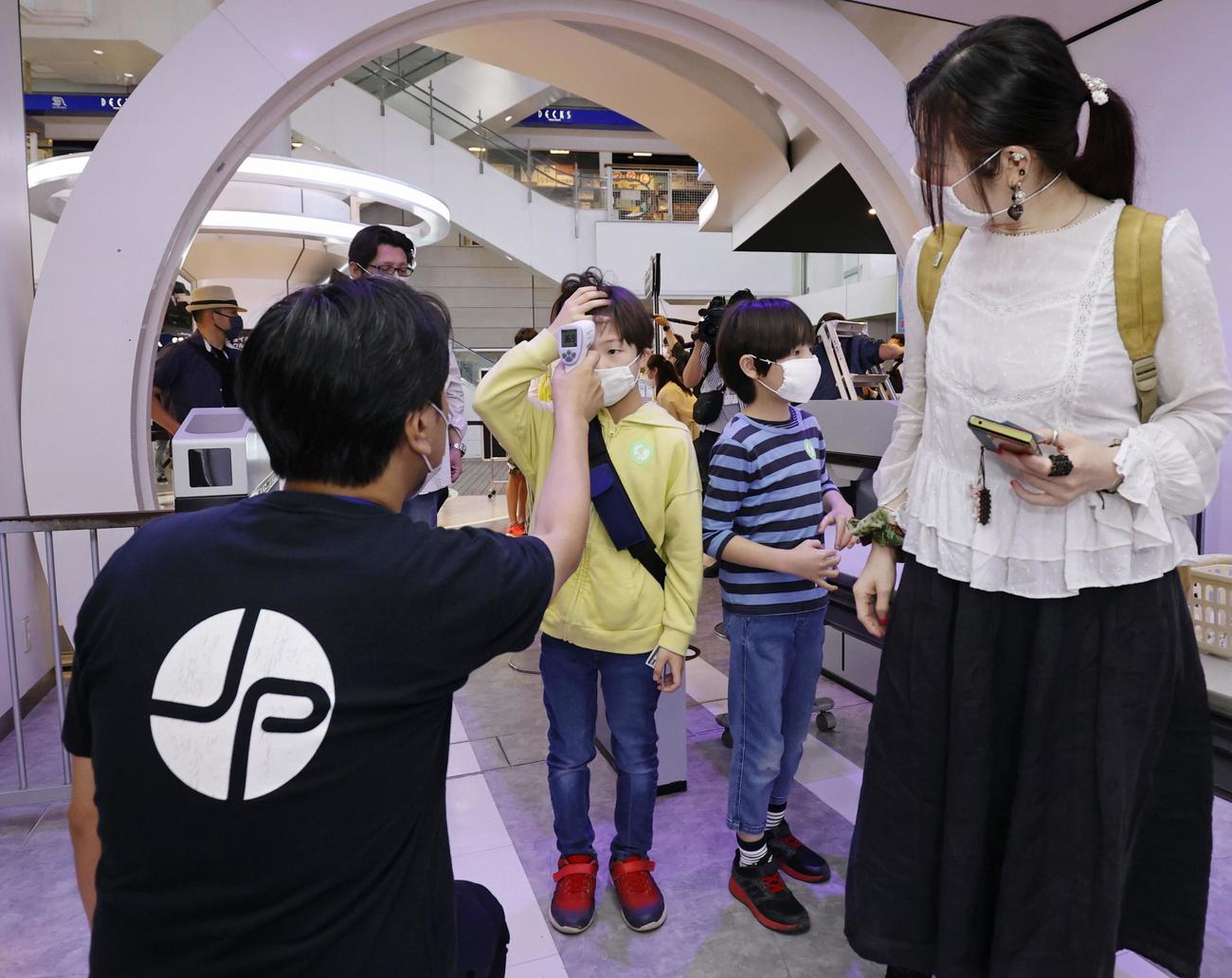 営業を再開した「東京ジョイポリス」で、入館時に検温を受ける子どもたち（共同）