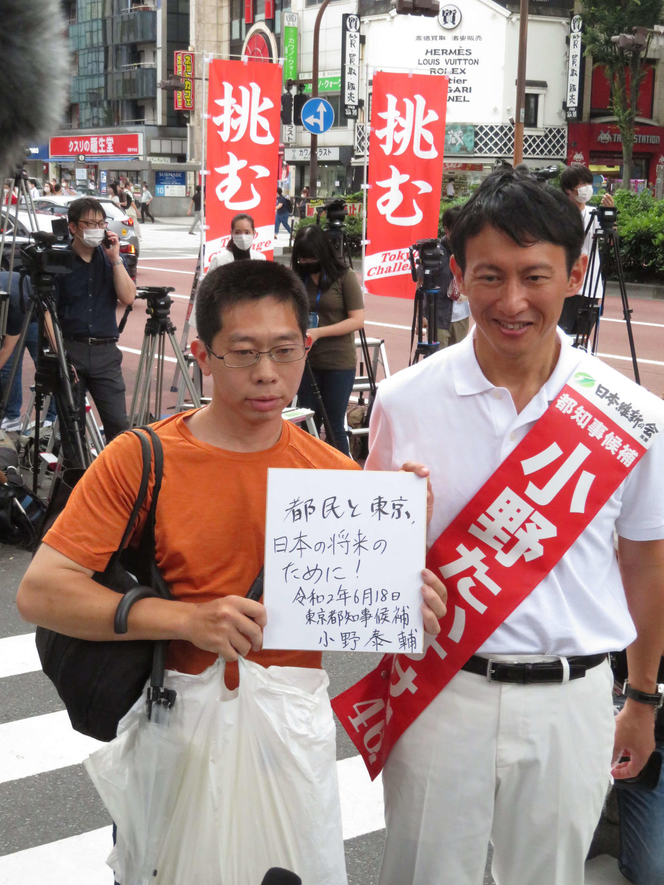 東京都新宿区歌舞伎町1丁目で都知事選の第一声を行った後、有権者の求めにサインを書いた小野泰輔氏（右）（撮影・村上幸将）