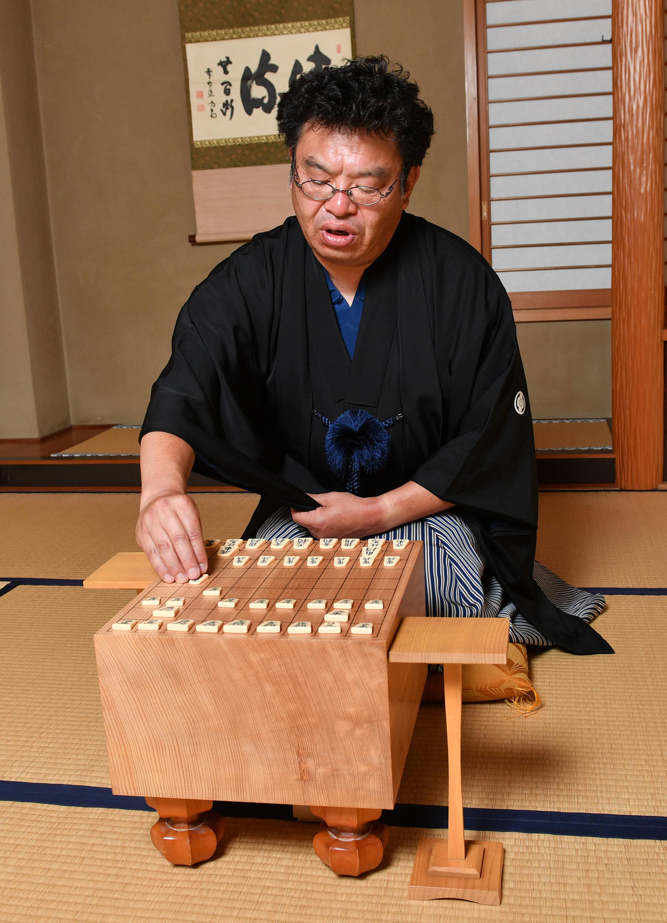 羽織はかま姿で将棋盤に向かい駒を持って指す赤塚記者（撮影・柴田隆二）