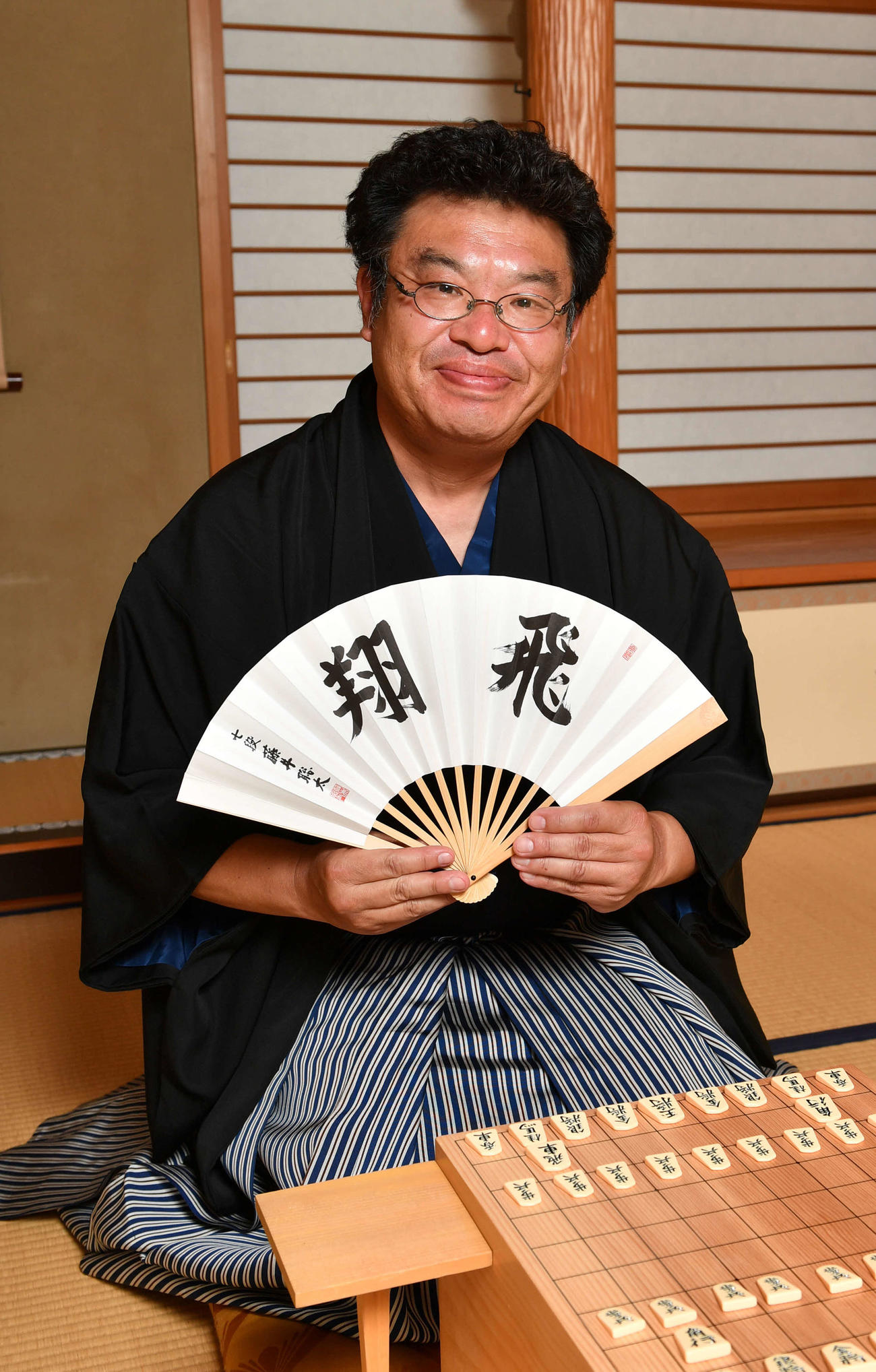 羽織はかま姿の赤塚記者は藤井聡太「飛翔」の扇子を持つ（撮影・柴田隆二）