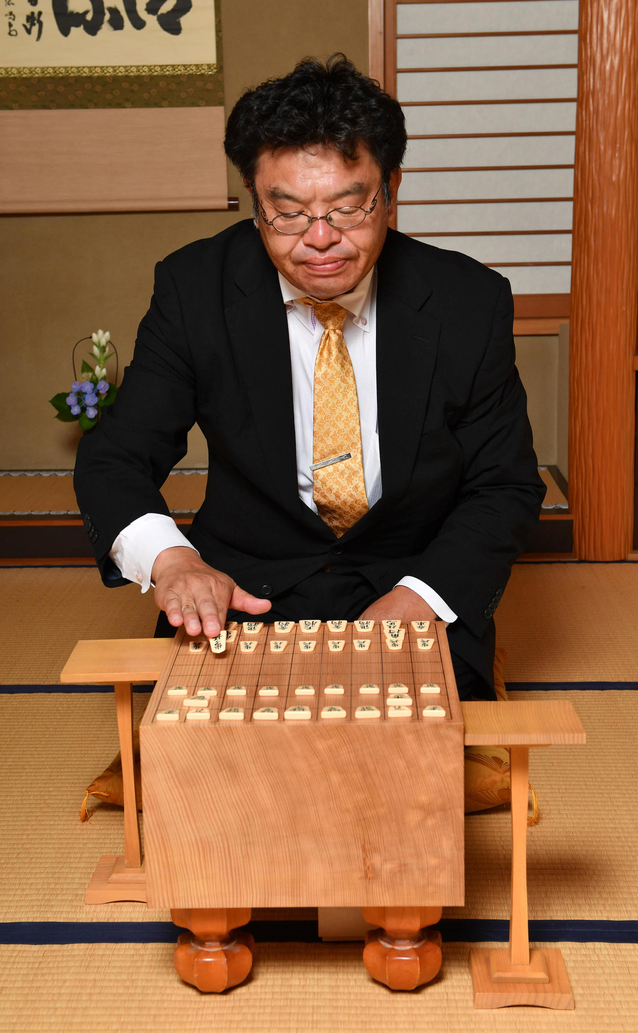羽織はかまの着付け前に、背広姿で将棋を指す赤塚記者（撮影・柴田隆二）
