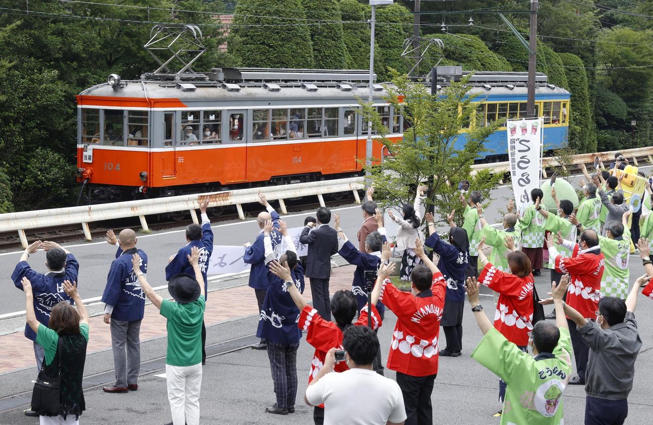 運行を再開した箱根登山鉄道の電車に向かい、手を振って出迎える地元住民ら（共同）