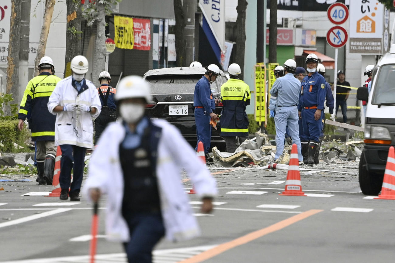 がれきが散乱する爆発現場周辺を調べる消防隊員ら＝30日午後0時29分、福島県郡山市（共同）