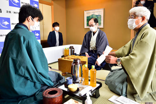 立会人の淡路仁茂九段(右)から木村一基王位の封じ手を見せられる藤井聡太棋聖(左)(日本将棋連盟)