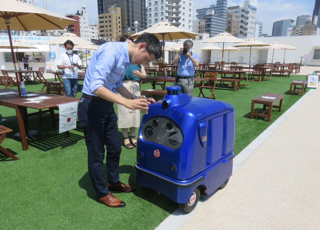 JR高輪ゲートウェイ駅前の特設会場で自動運転ロボット「デリロ」が出前の実証実験を行い、料金をスマホで決済した（撮影・大上悟）