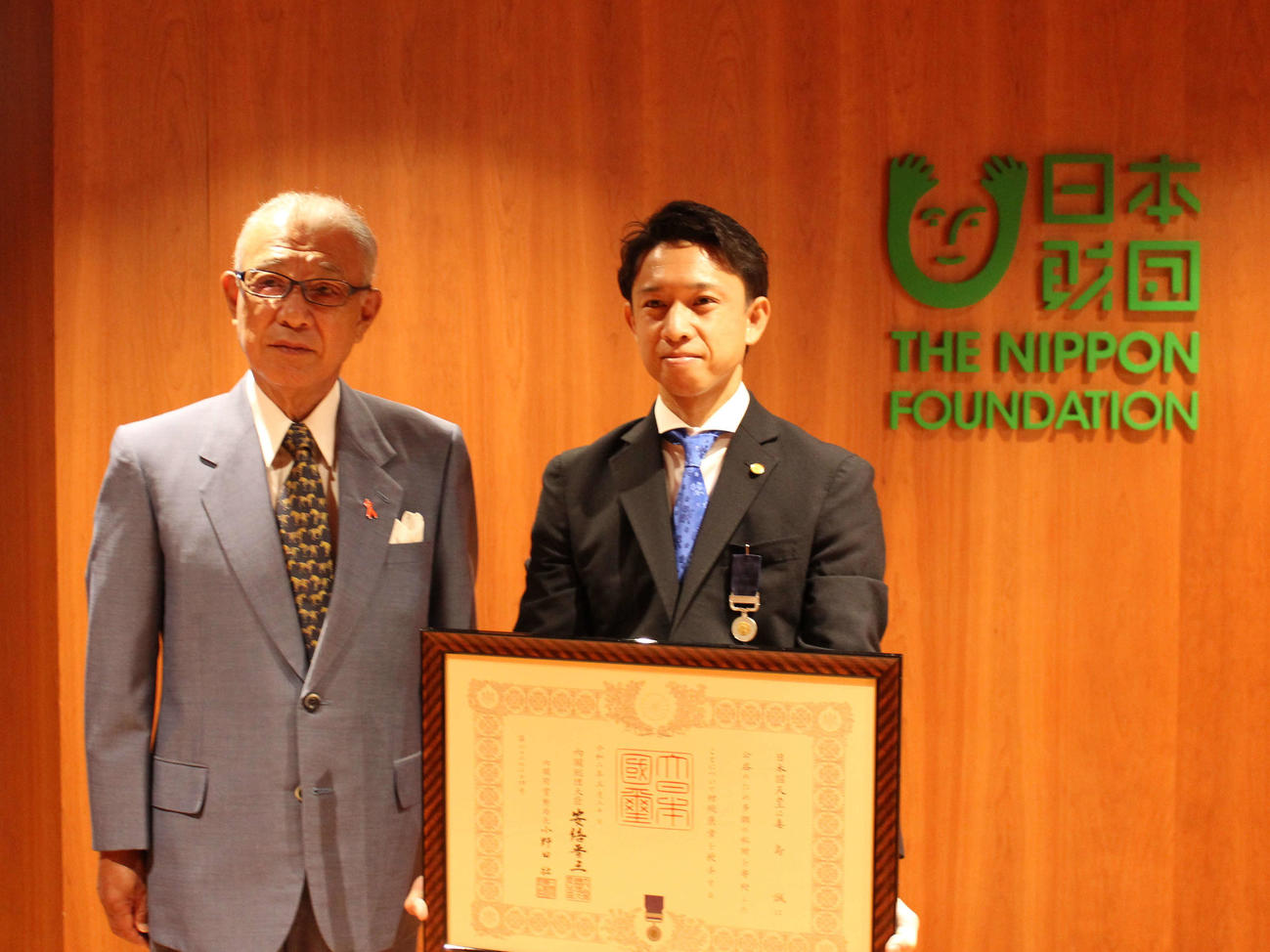 日本財団笹川陽平会長（左）から紺綬褒章が伝達された毒島誠