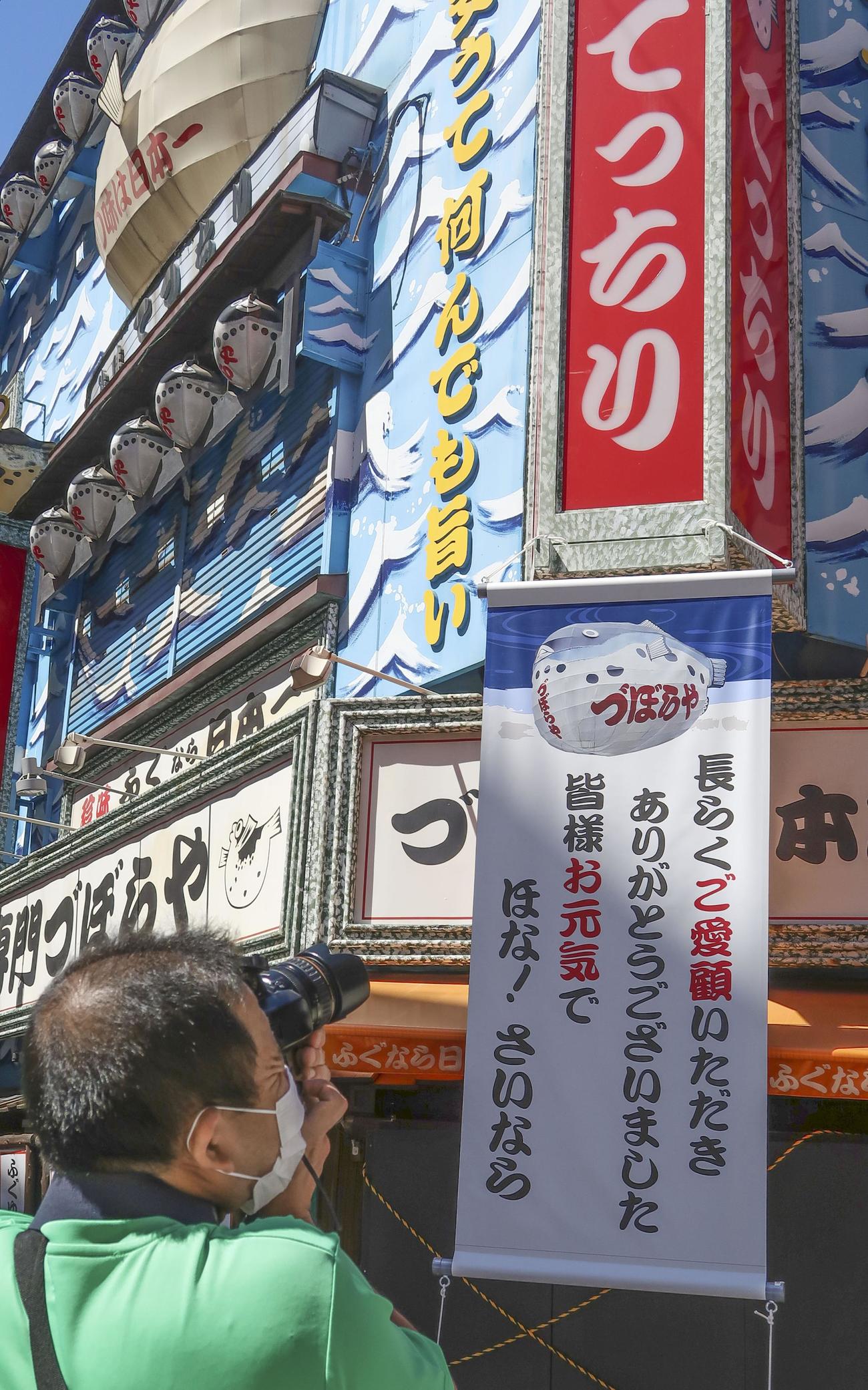 「づぼらや」入り口付近の「ほな！さいなら」などと書かれた垂れ幕（下）（共同）