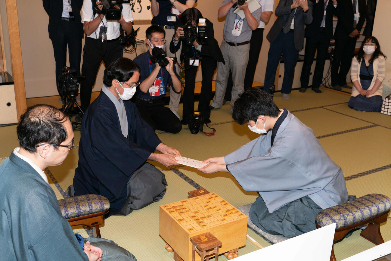 藤井聡太七段（右）が王位戦7番勝負第2局で初めて行った封じ手（中央は立会人の深浦康市九段、左は木村一基王位、段位・肩書は当時、日本将棋連盟提供）