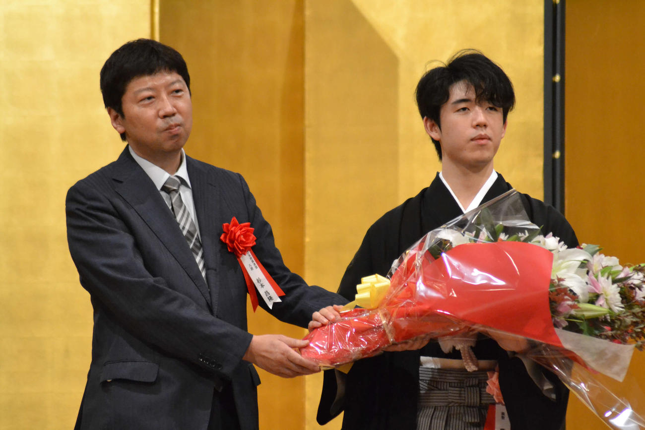 藤井聡太棋聖（右）は就位式で師匠の杉本昌隆八段から花束を贈呈される