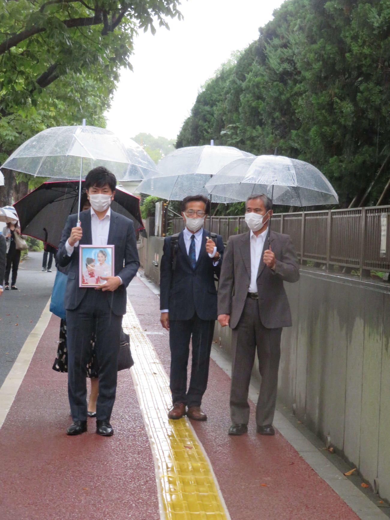 亡くなった真菜さんと莉子ちゃんの遺影を手に、東京地裁に入る松永拓也さん（左）と義父の上原義教さん（撮影・村上幸将）