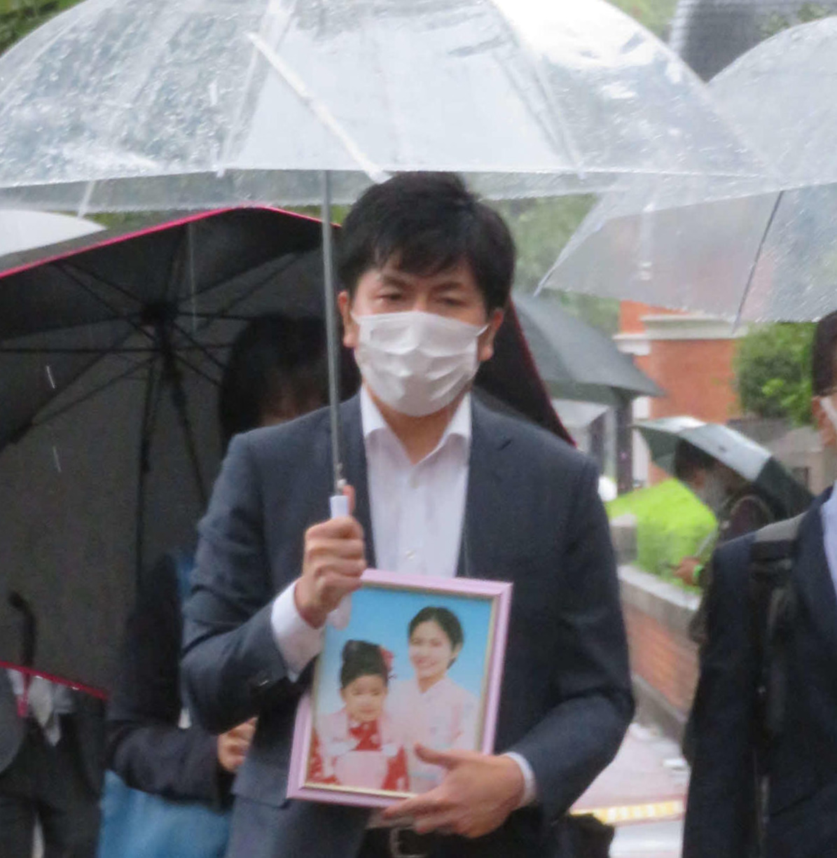 亡くなった真菜さんと莉子ちゃんの遺影を手に、東京地裁に入る松永拓也さん（撮影・村上幸将）
