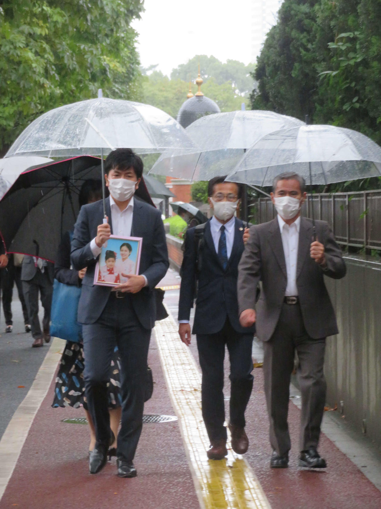 亡くなった真菜さんと莉子ちゃんの遺影を手に、東京地裁に入る松永拓也さん（左）と義父の上原義教さん（撮影・村上幸将）