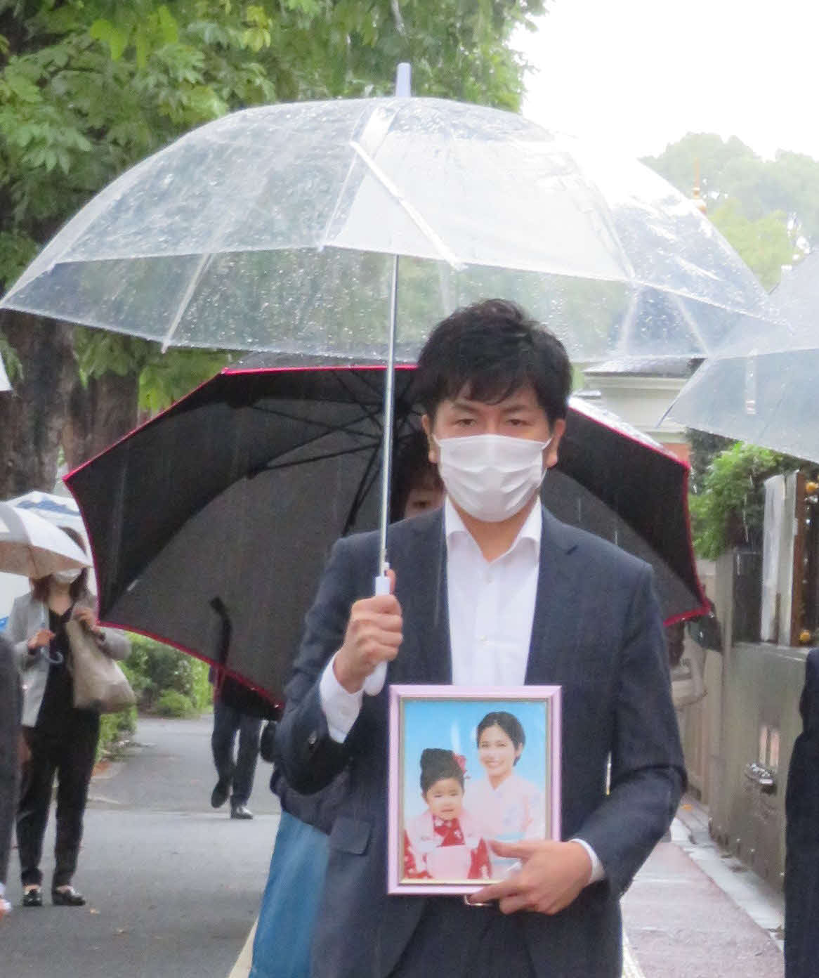 亡くなった真菜さんと莉子ちゃんの遺影を手に、東京地裁に入る松永拓也さん（撮影・村上幸将）