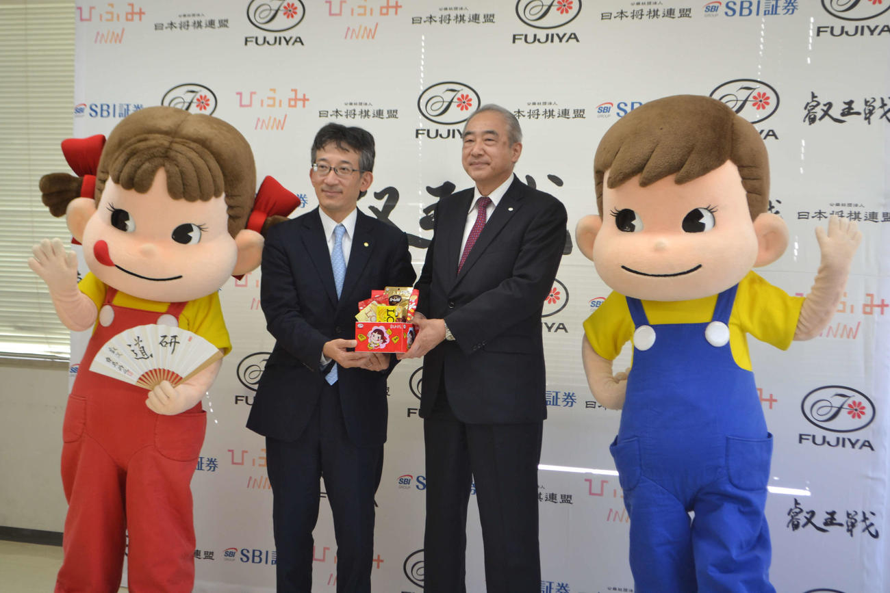 第6期叡王戦記者会見に出席した日本将棋連盟の佐藤康光会長（左）と不二家の河村宣行社長。左端が不二家マスコットキャラクターのペコちゃん、右端がポコちゃん