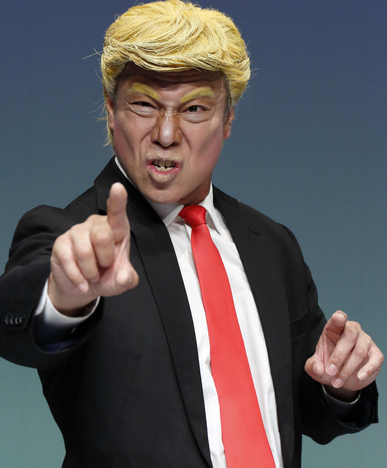 ザ・ニュースペーパーの松下アキラが扮するトランプ大統領。この金髪かつらを脱ぐと白髪頭のバイデン氏に早替わりできる