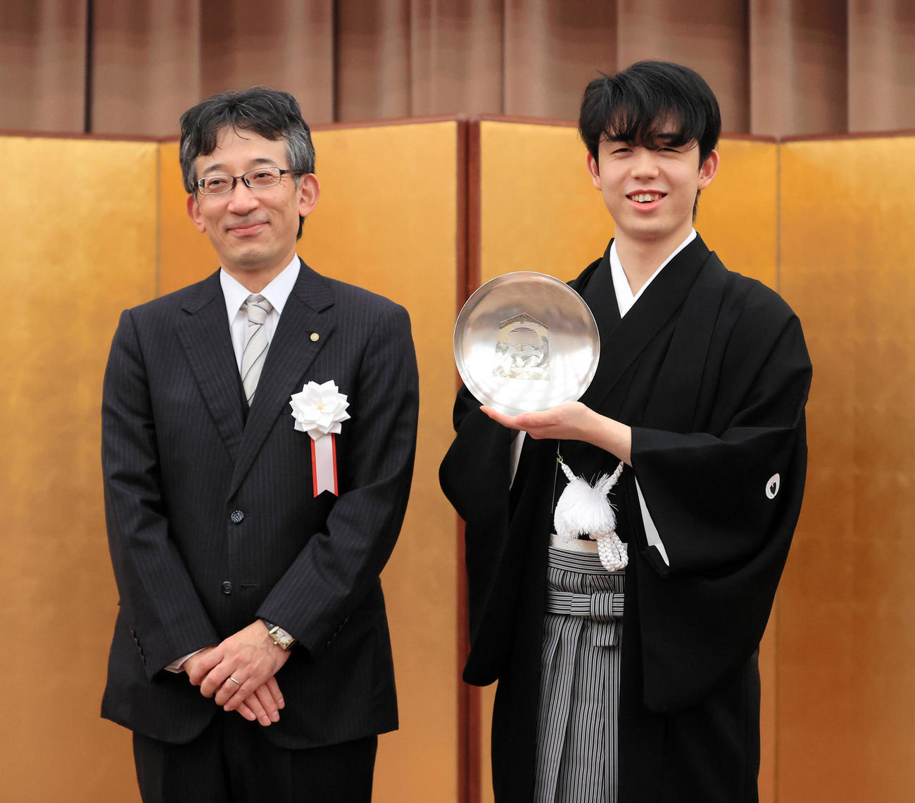 藤井王位就任式　王位就位式で王位杯を授与される藤井聡太王位。左は日本将棋連盟会長の佐藤康光九段（代表撮影）