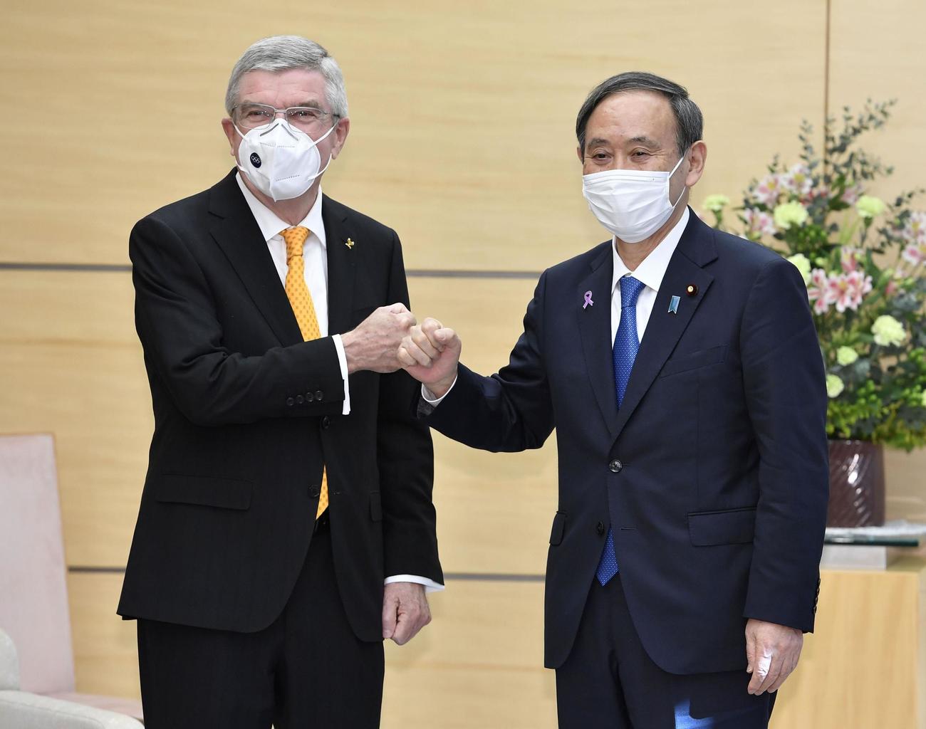 会談を前にIOCのバッハ会長（左）とグータッチを交わす菅首相（共同）