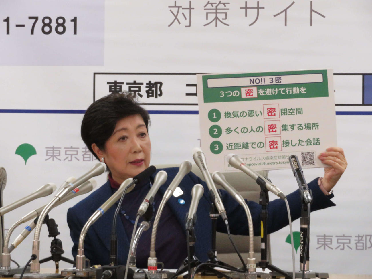 3月26日、緊急会見で、ボードを掲げて説明する小池百合子都知事