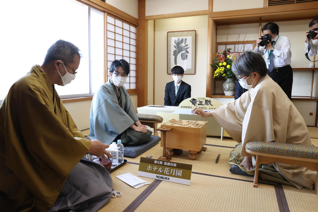 将棋第33期竜王戦7番勝負　第5局　封じ手を指す羽生善治九段（右）と封じ手用紙を確認する豊島将之竜王（左から2人目、左は立会人の中村修九段）（代表撮影）
