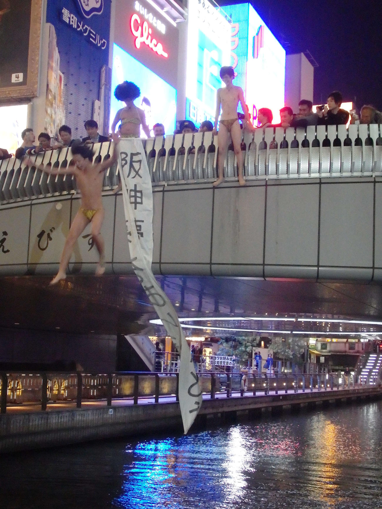 「阪神夢をありがとう」の垂れ幕を掲げ、戎橋から道頓堀川に向かって飛び降りる男性グループ（2014年10月30日撮影）