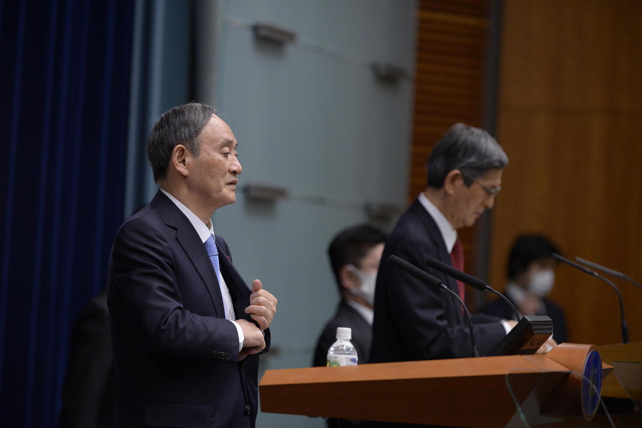 プロンプターを使って会見する菅首相。後方は尾身会長（AP）