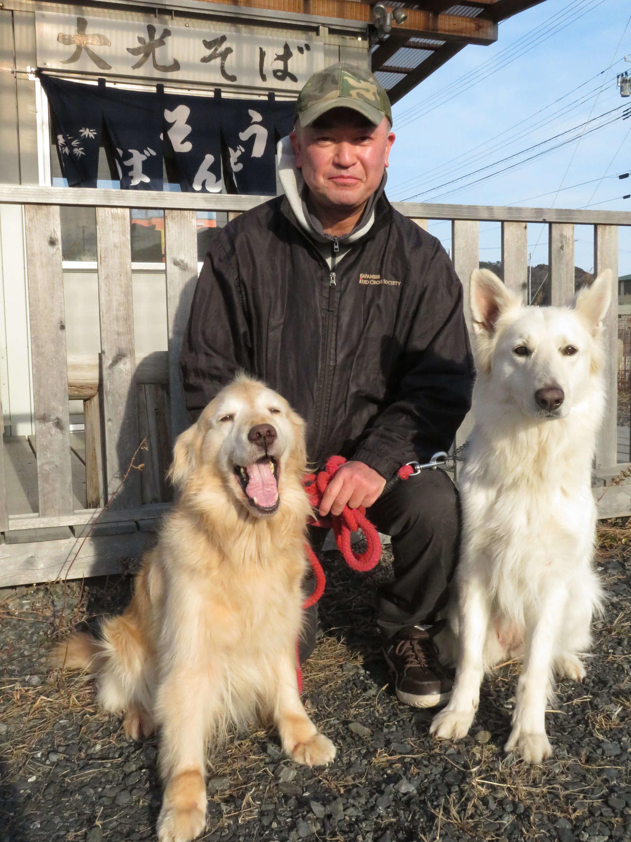 経営する立ち食いそば店の前で、災害救助犬「ゆき」（左）と「さち」（右）について語る飼い主の佐々木光義さん（撮影・近藤由美子）