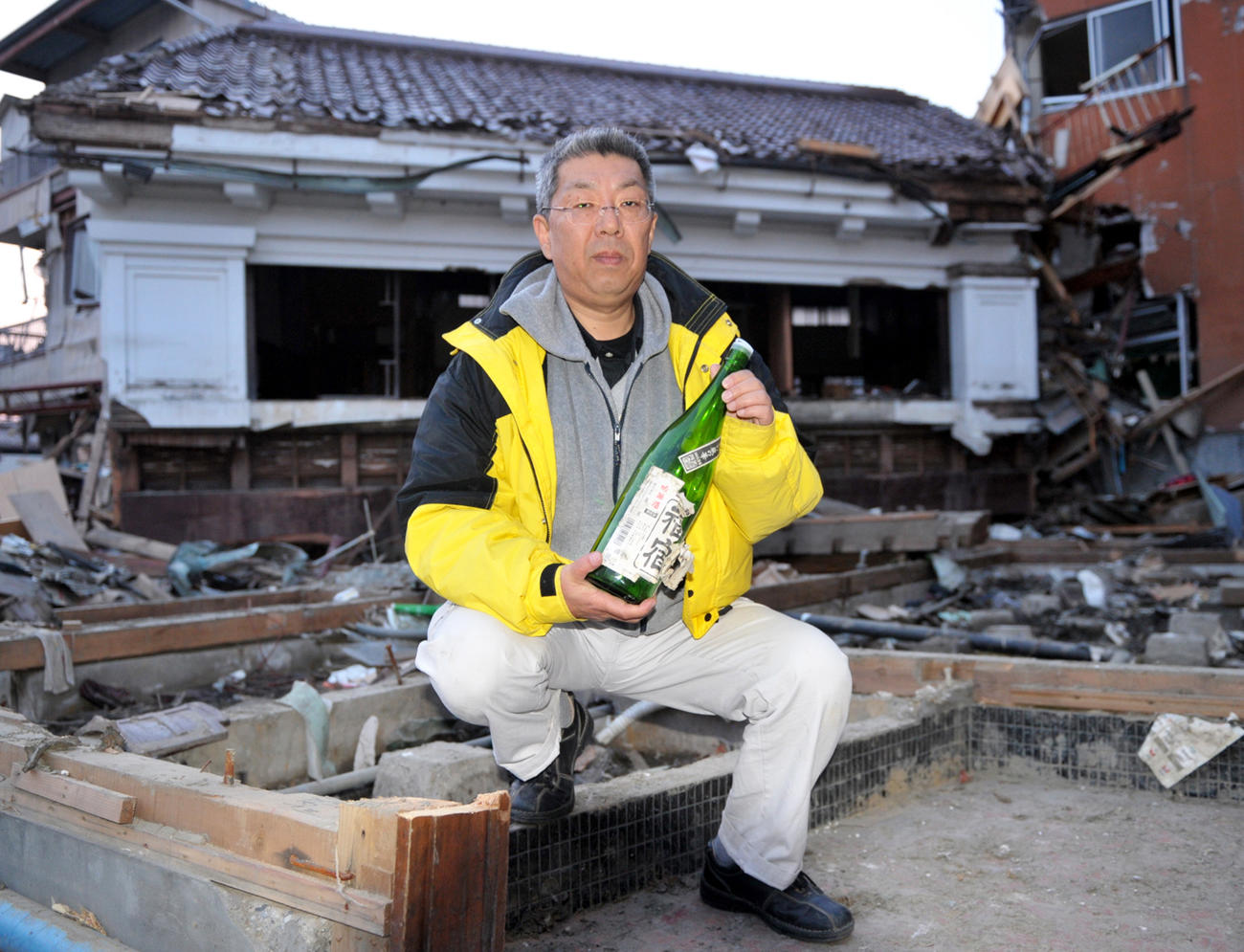 11年3月、津波で倒壊した土蔵から奇跡的に生き残った一升瓶を手にする「角星」の斉藤嘉一郎社長