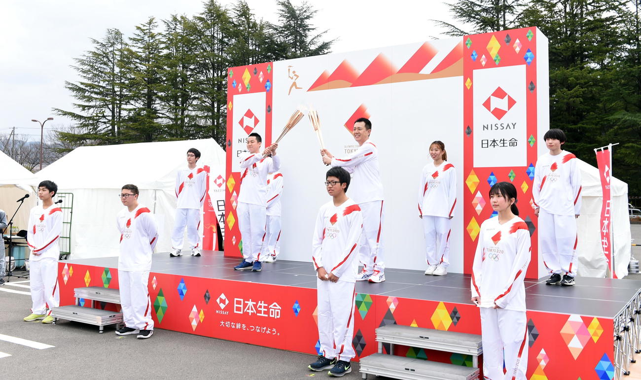 東京五輪聖火リレーイベントでトーチキスをする神酒太郎さん（2列目左）と日本生命・桜井英樹福島支社長（同右）（撮影・山田愛斗）