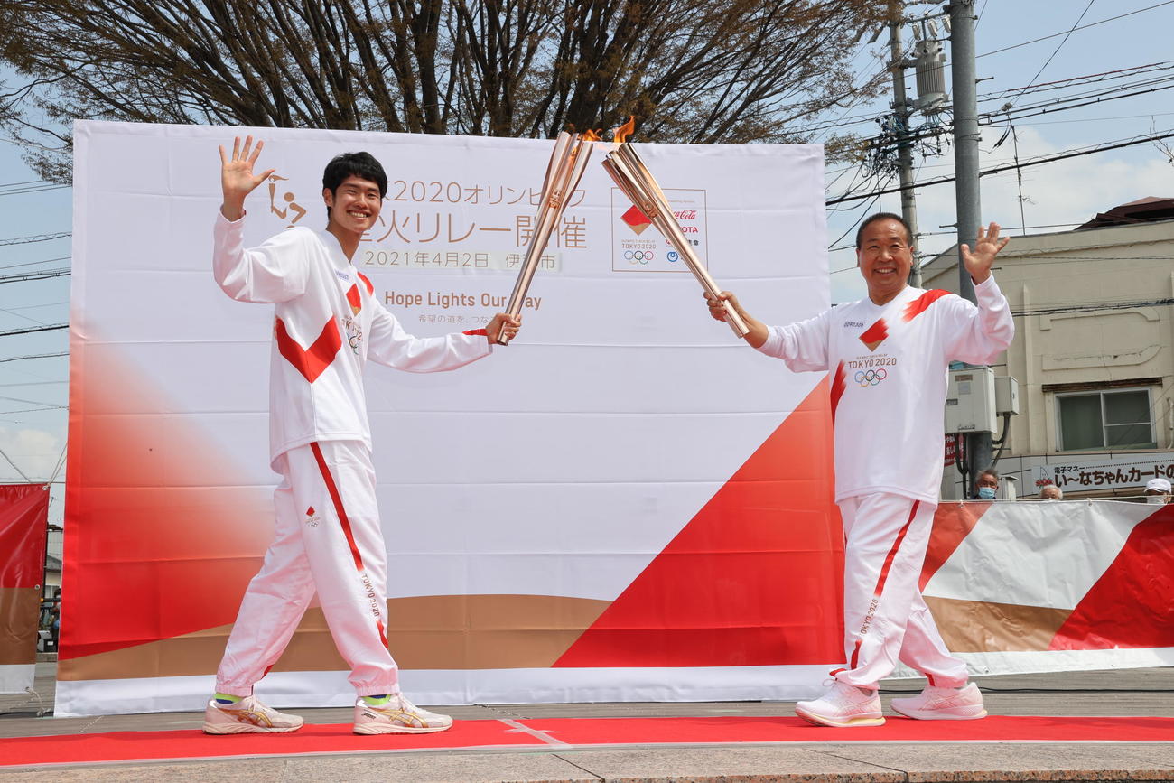 聖火ランナーを務めた元陸上選手の伊藤国光さん（右）は次走者の伊藤大志さんとトーチキスを行う（代表撮影）