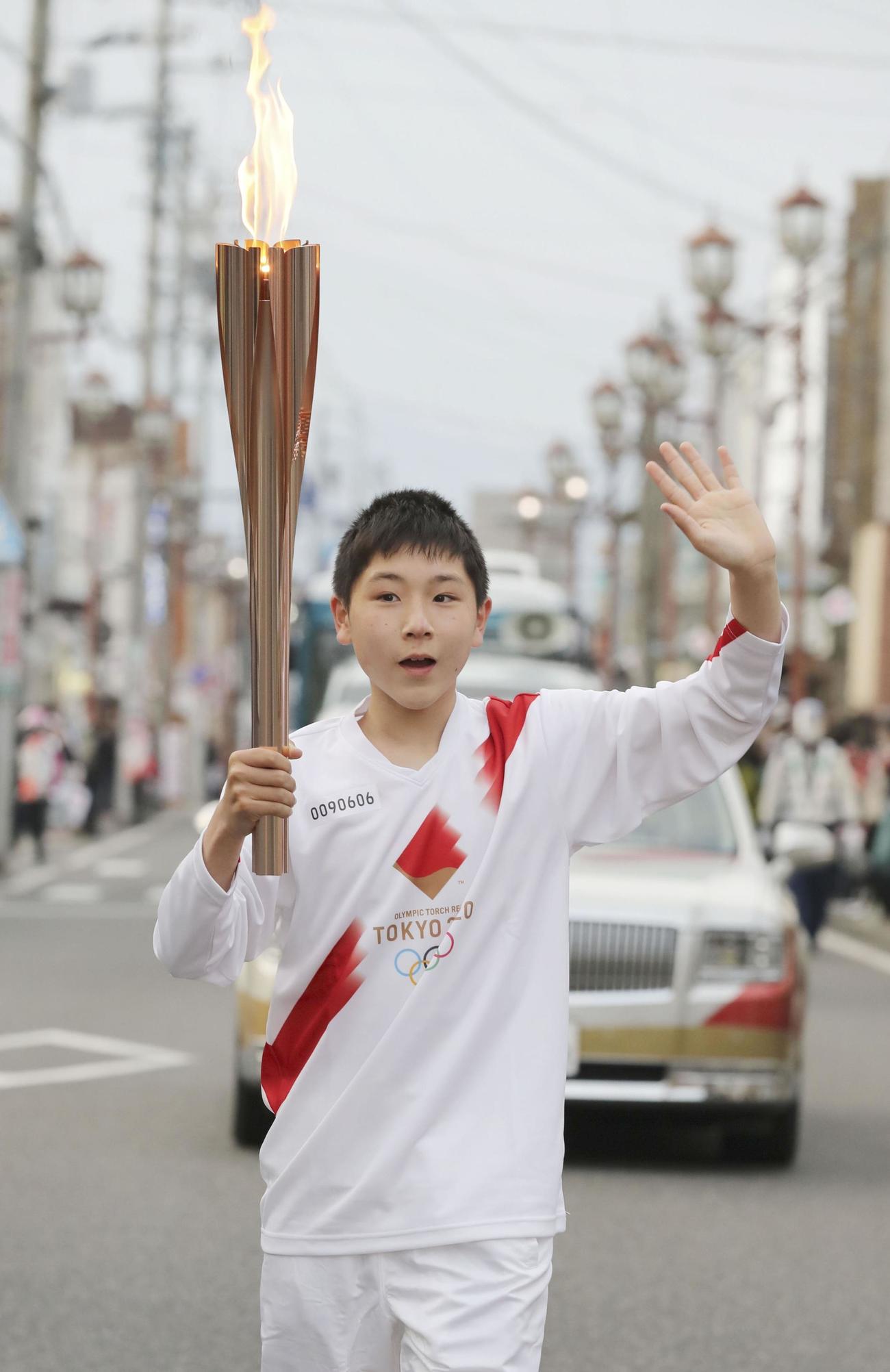 トーチを掲げて走る聖火ランナーの関野佑平さん（共同）