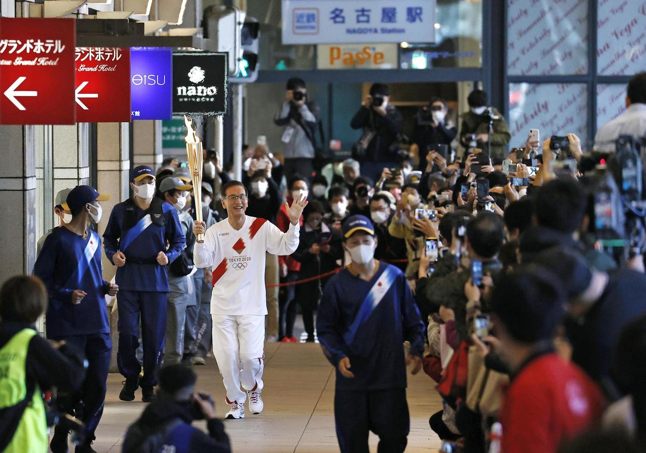 大勢の人たちが見守る中、名古屋駅前を走る聖火ランナー（共同）