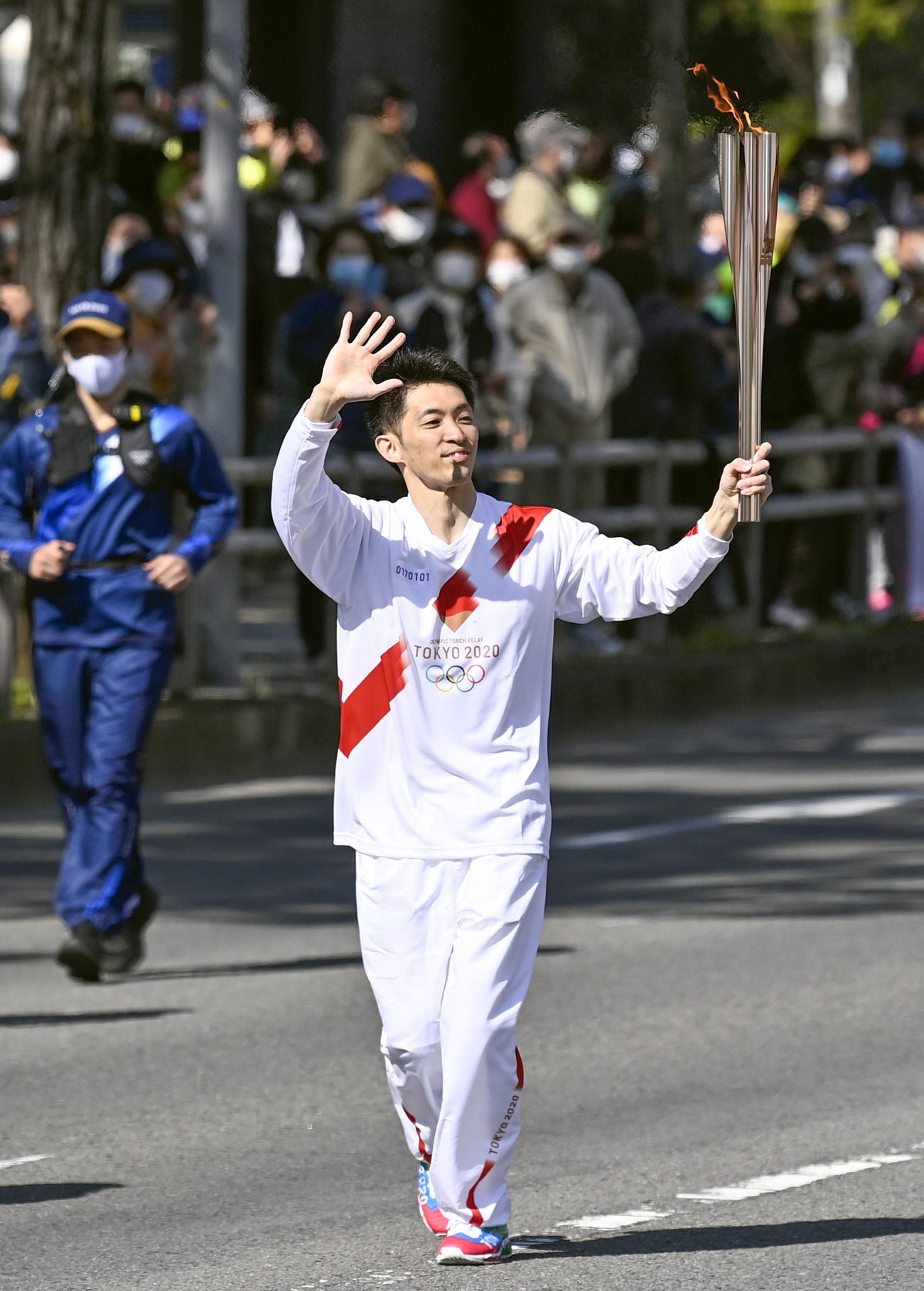 聖火のトーチを掲げて走る田中和仁さん（共同）