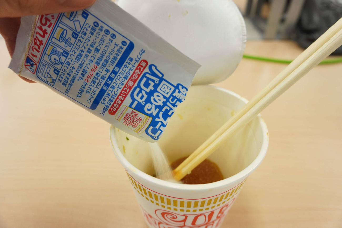 日清食品のカップヌードルに残ったスープ固めるパウダーを入れる様子（撮影・沢田直人）