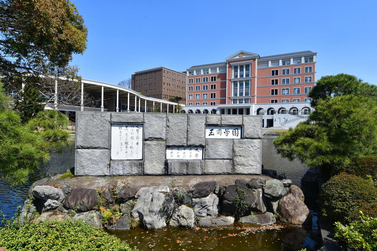 町田市にある玉川学園キャンパスの正門や教育棟（奥）（玉川学園提供）