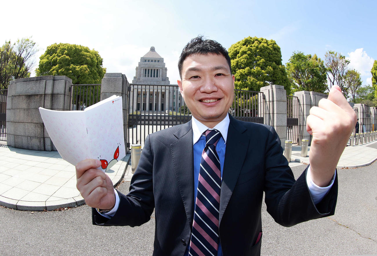 国会議事堂を背に、メモ帳を手にしてガッツポーズするTBSの澤田大樹記者（撮影・浅見桂子）