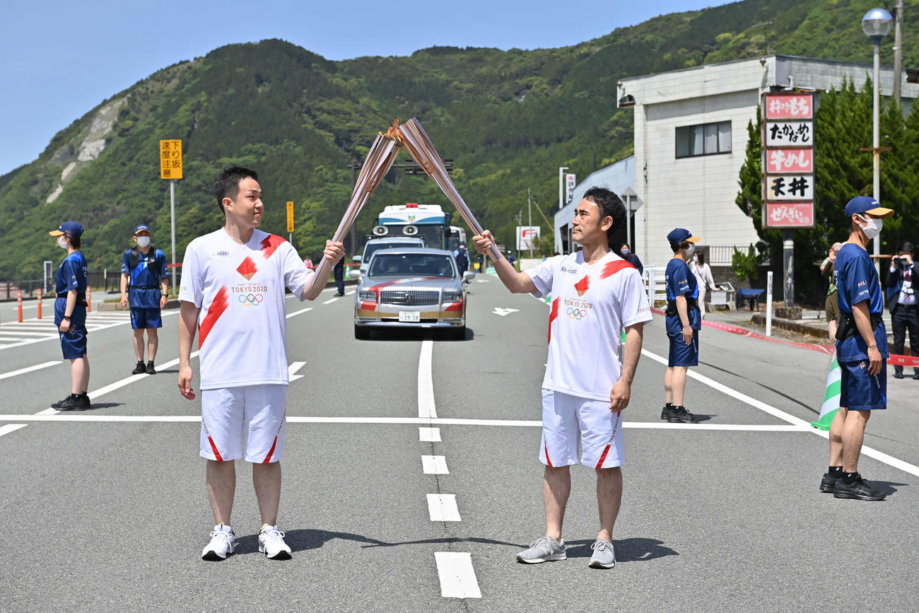聖火ランナーを務めた河津謙二さん（右）は前走者船木崇史さんとトーチキスを行う（代表撮影）