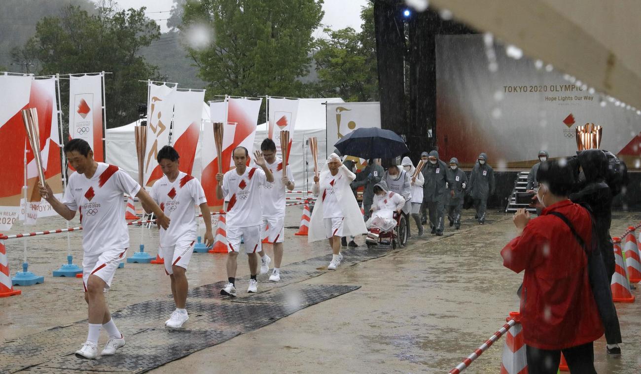 雨の中、聖火リレー代替イベントでトーチキスを終えたランナーら（共同）
