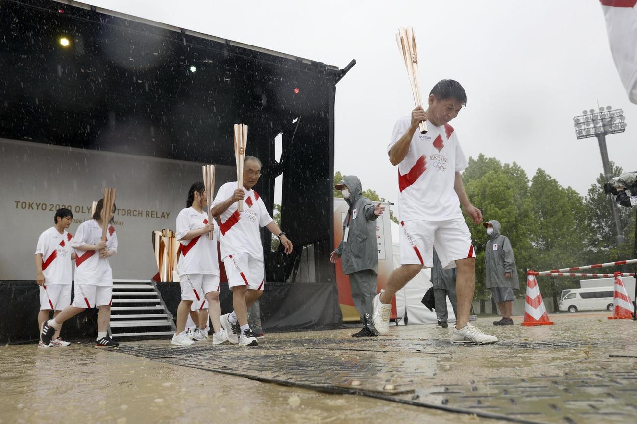 雨の中、トーチキスを終えたランナー（共同）