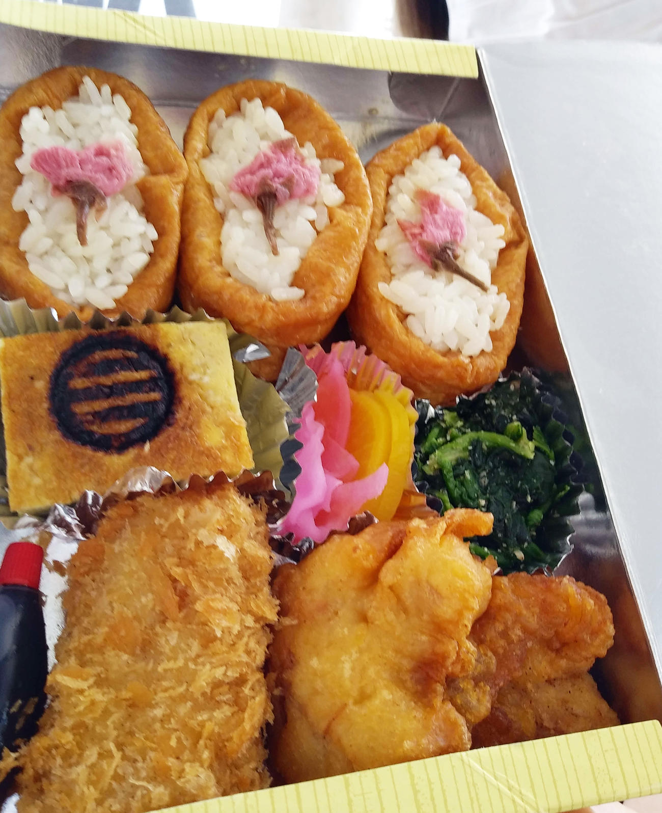衣笠駅　カラオケスナック「歌楽屋」の「三浦氏出陣桜弁当」いなり3つに桜の塩漬けのワンポイント（撮影・寺沢卓）