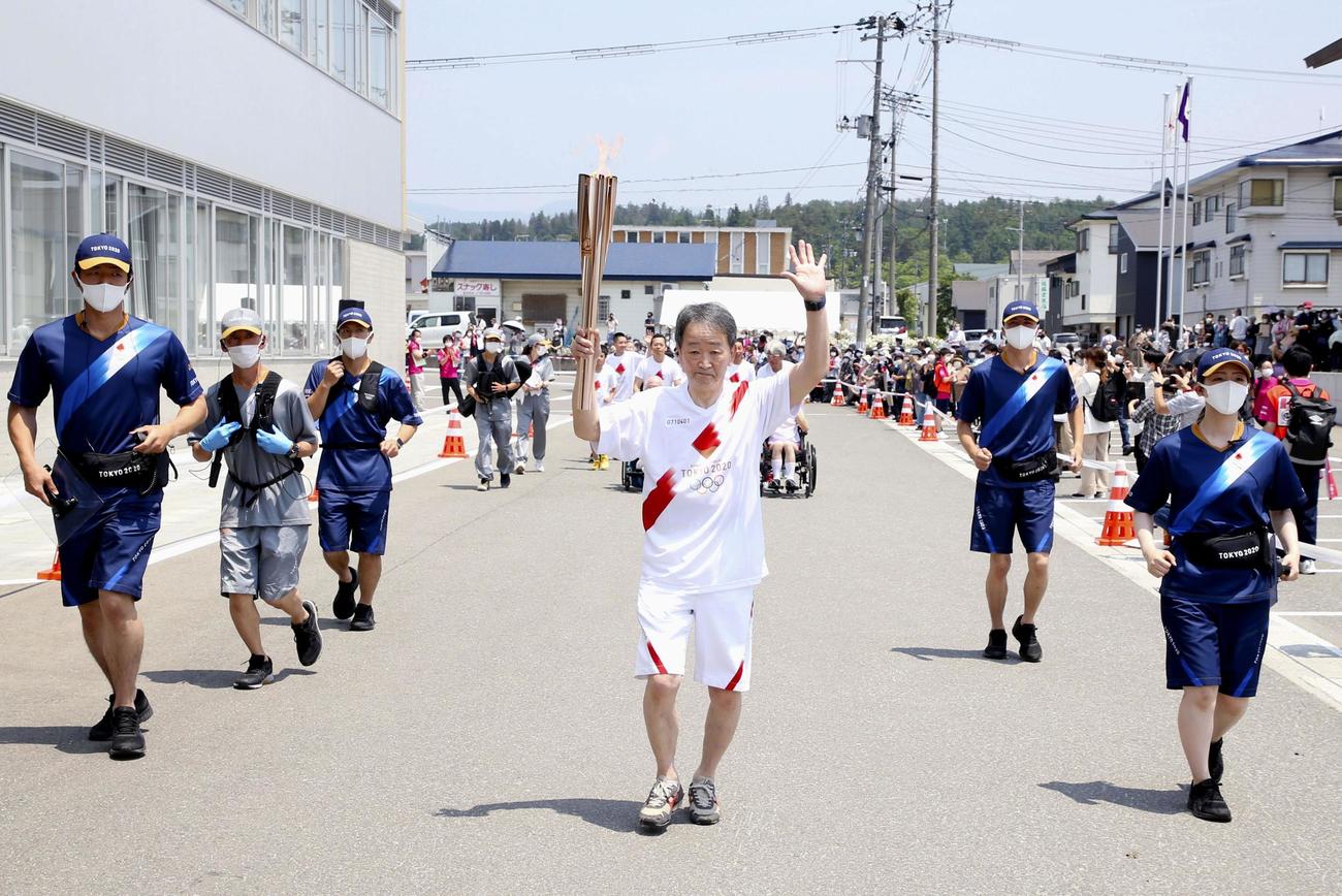 トーチを掲げて走る聖火ランナーの菅藤弘さん(共同)
