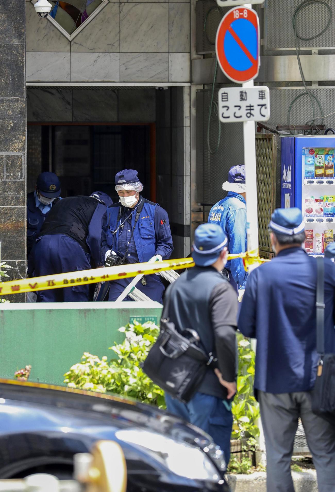 女性の遺体が見つかった雑居ビルを調べる警察官ら（共同）