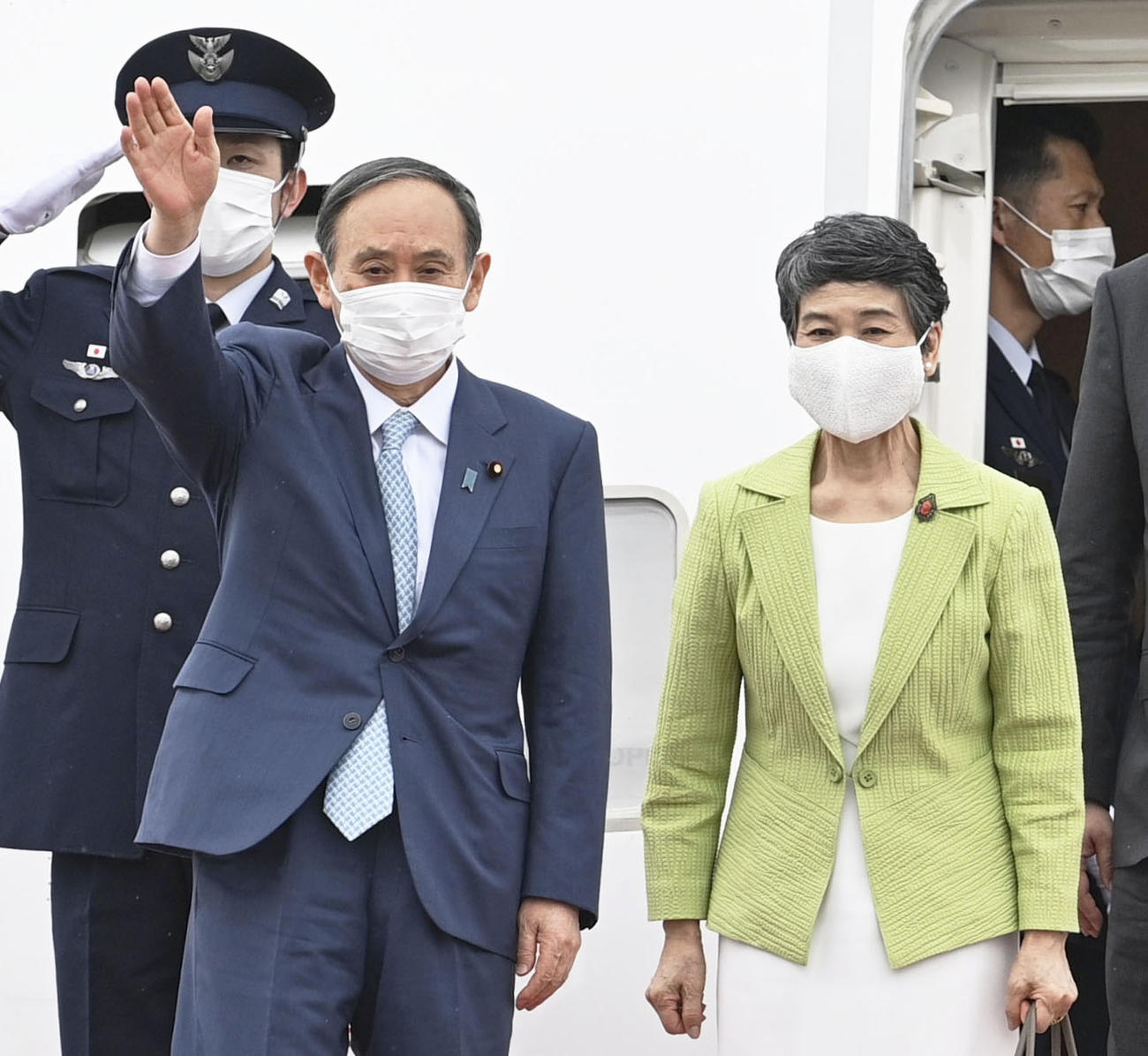 G7サミットを終え英国から帰国し、手を振る菅首相。右は真理子夫人