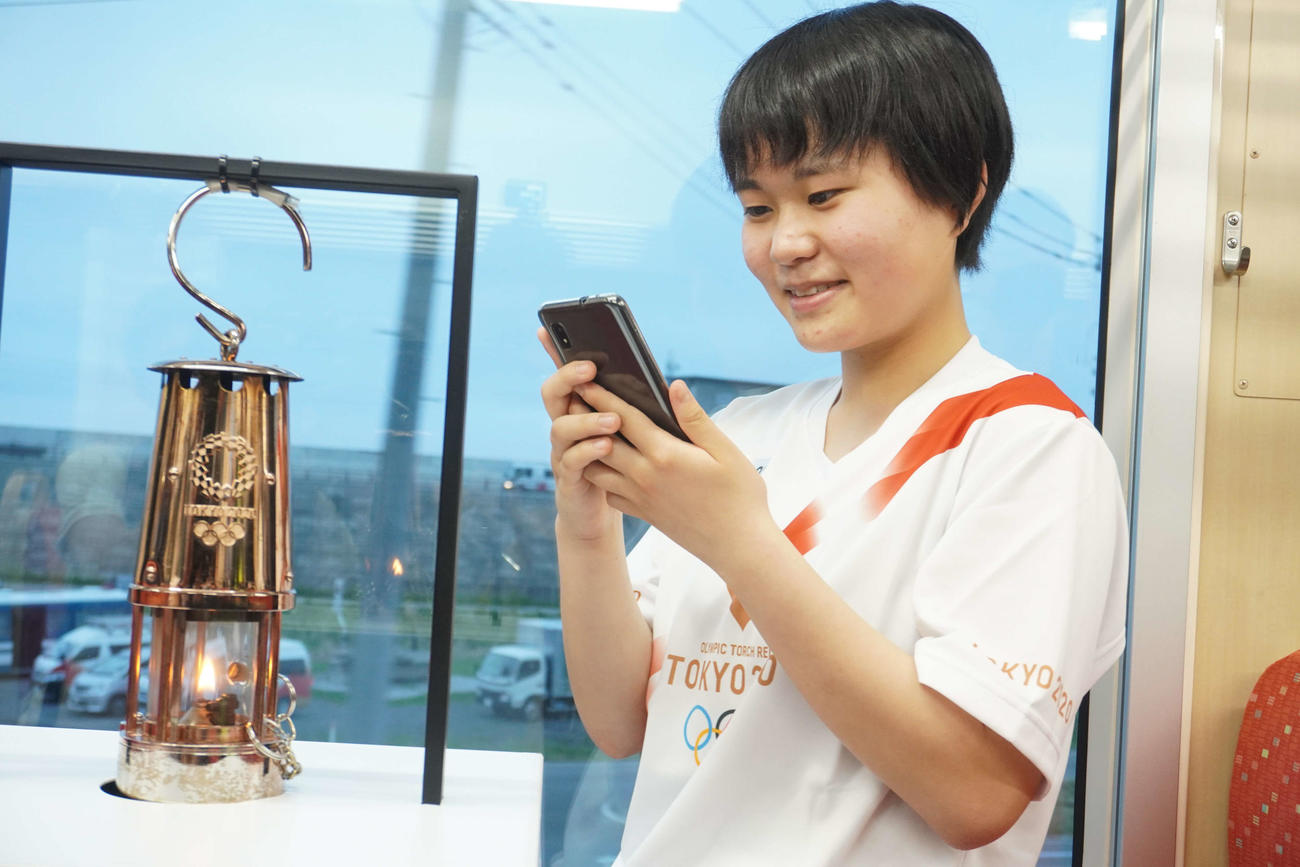 三陸鉄道の車内で聖火をスマートフォンで記念撮影する金子恵美さん（撮影・沢田直人）