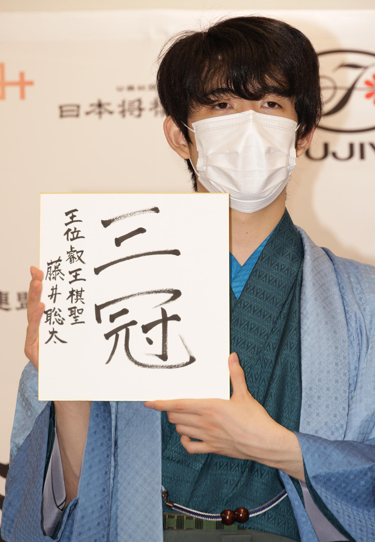 史上初の10代3冠を達成した藤井新叡王は、色紙を掲げる（撮影・中島郁夫）