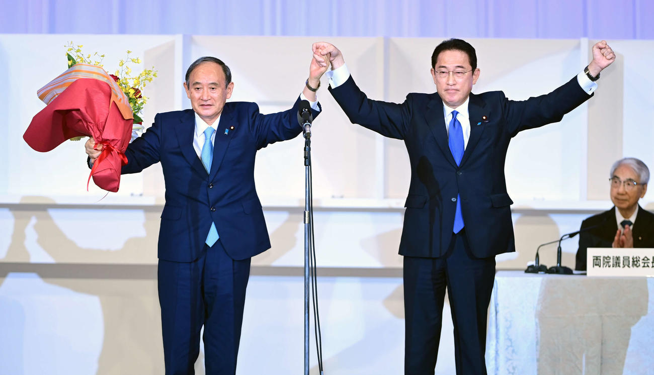 自民党総裁選を終え万歳する菅義偉前総裁（左）と岸田文雄新総裁（撮影・小沢裕）